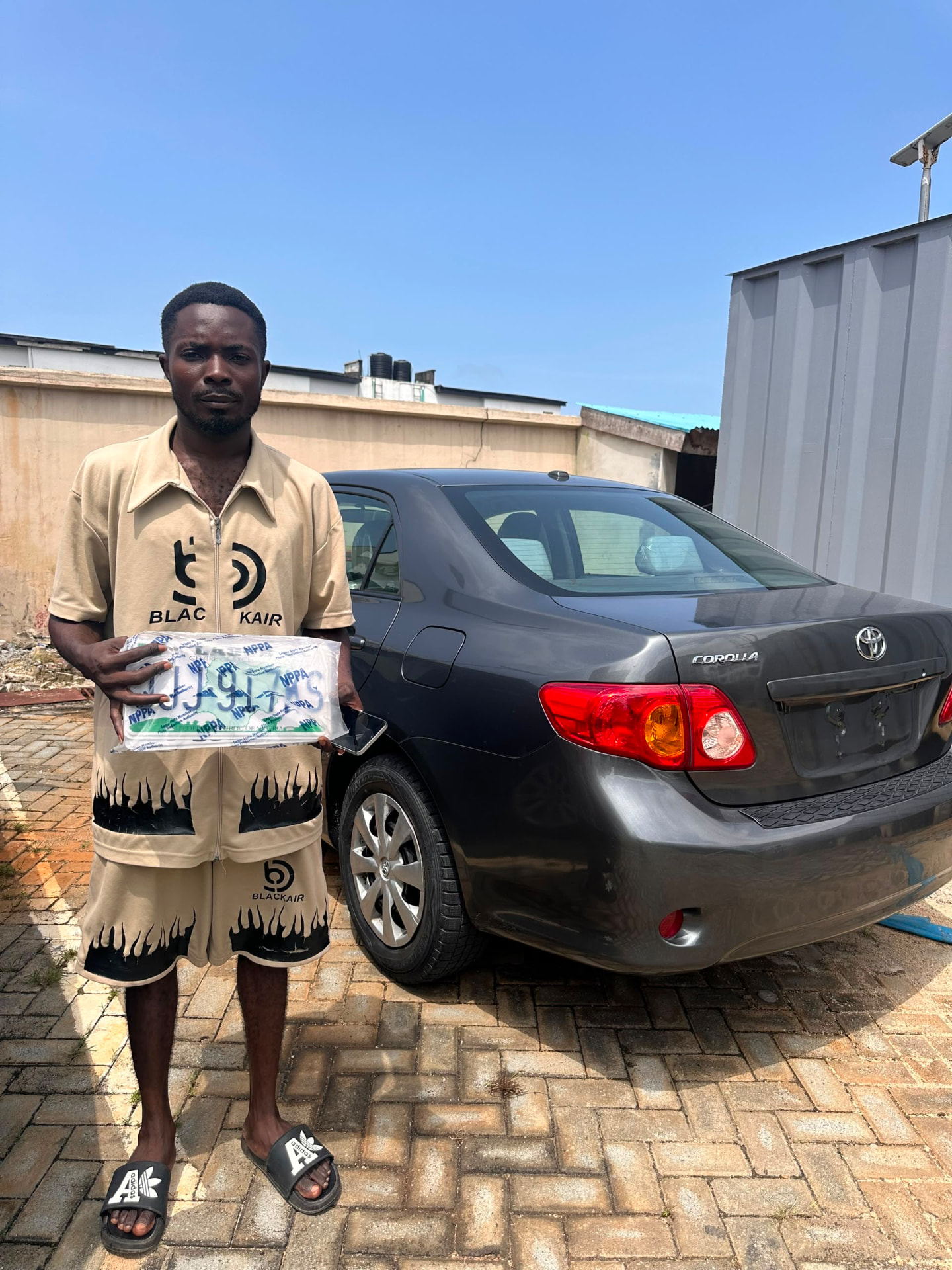 Green Autos customer standing beside his grey Toyota Corolla