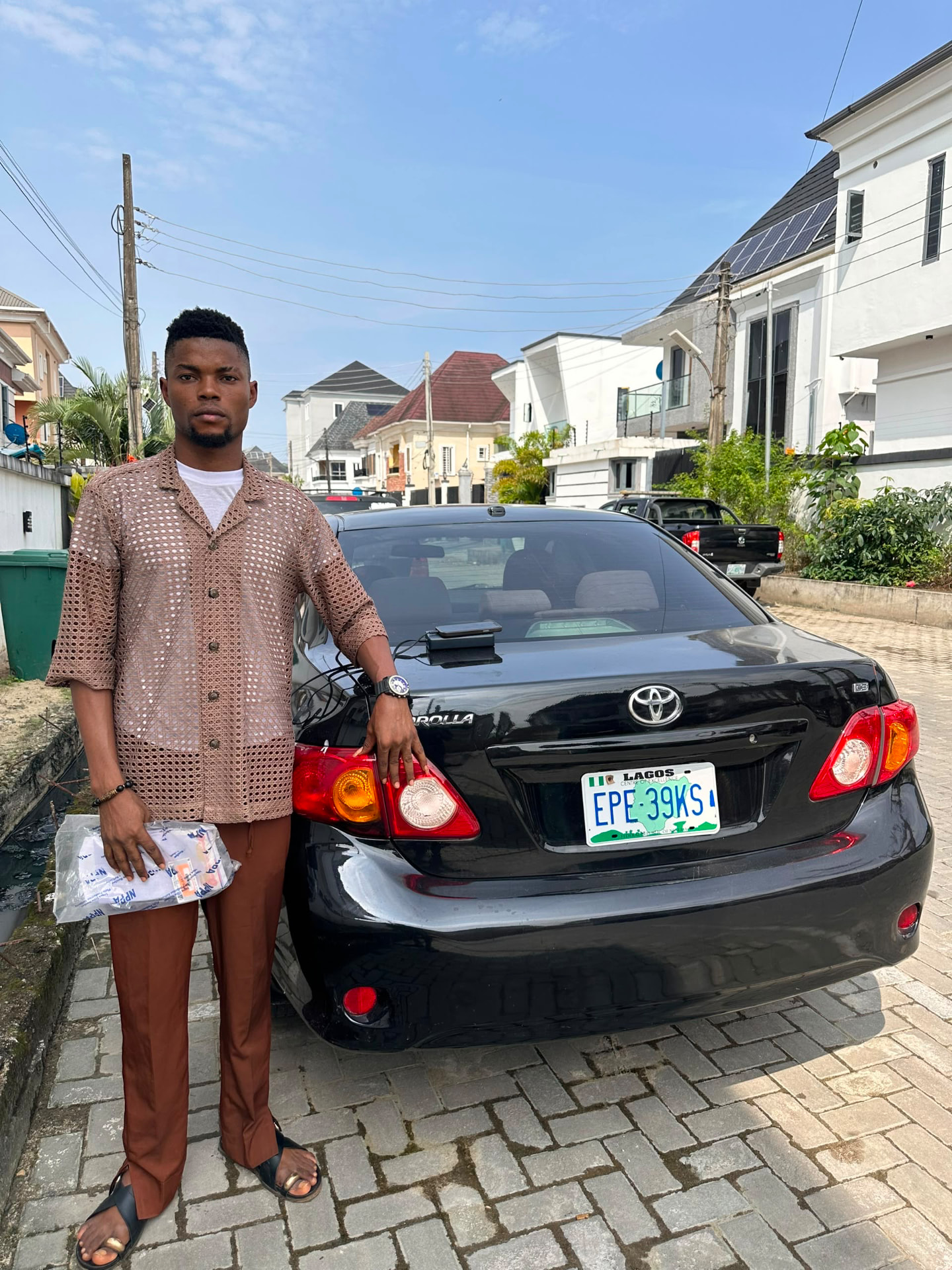 Green Autos customer standing beside his black Toyota Corolla