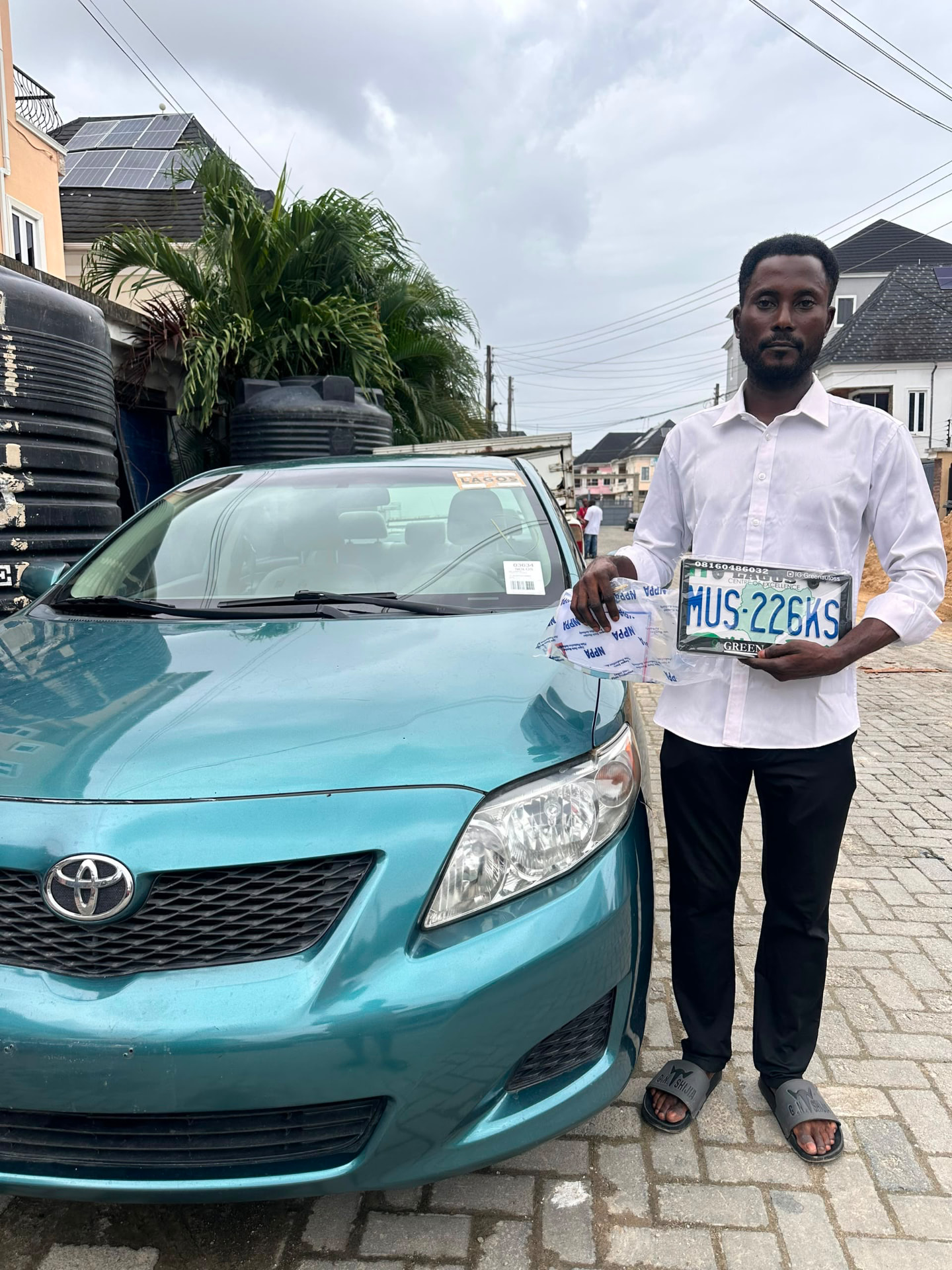 Green Autos customer standing beside his teal Toyota Corolla